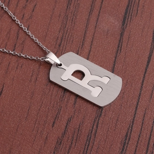 Vue détaillée du collier en acier inoxydable avec pendentif lettre R sur bois brun