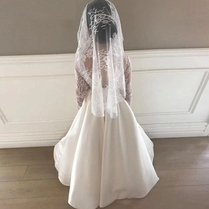 White lace long sleeve satin flower girl dress with long lace veil shown from the back view