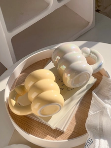Top view of two bubble-shaped ceramic mugs in pastel yellow and pearlescent white