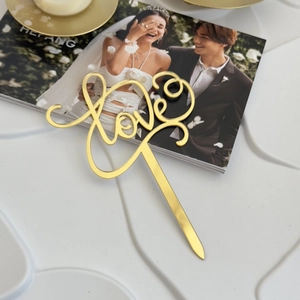 Close-up of golden mirror acrylic Love cake topper for wedding and Valentine's Day decor