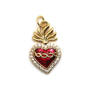 Macro view of gold sacred heart pendant with red enamel and sparkling zircon stones