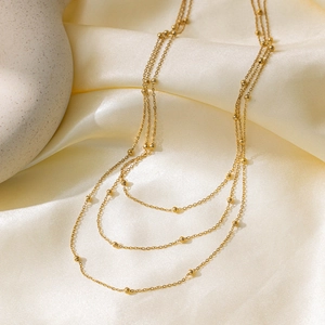 Elegant multi-layer gold beaded chain necklace on smooth silk with a minimalist design