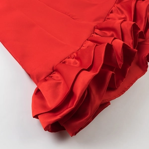 Close-up of bright red satin dress featuring tiered ruffle details and silky texture
