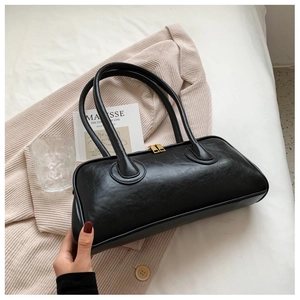 Detail of black faux leather handbag with double top handles and gold-toned dual zippers