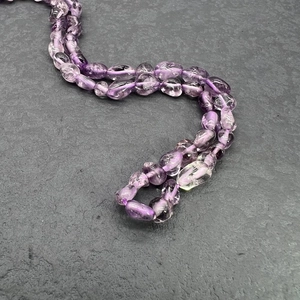 Macro shot of natural irregular purple amethyst beads on a textured dark rock background