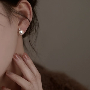 Close-up of a model wearing the crown shaped pearl earring with golden zircon detail