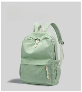 Detail view of green corduroy backpack showing fabric texture and woven zipper pullers