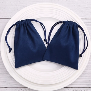 Pair of dark blue flannel drawstring jewelry pouches on a white ceramic plate