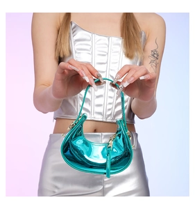 Macro detail of glossy metallic turquoise crescent handbag with golden hardware