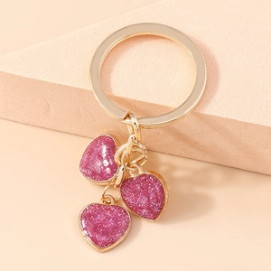 Detail of three-tier pink glitter heart pendants with golden ring keychain attachment