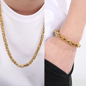 Golden Byzantine style stainless steel necklace and bracelet set for men on white t-shirt
