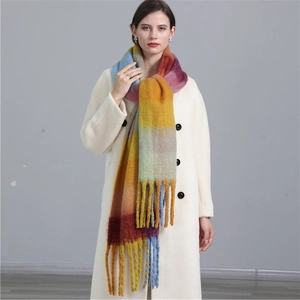 Détail d'une écharpe douce à carreaux arc-en-ciel avec des franges sur manteau blanc