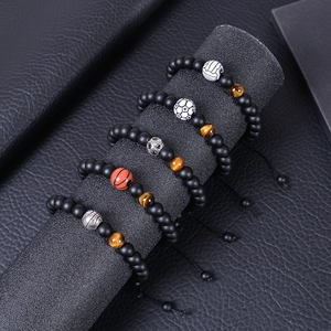Detail view of five sports beaded bracelets with soccer and basketball charms on a stand