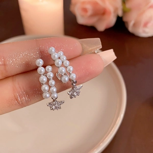 Detailed close-up of silver star earrings with white pearls and sparkling cubic zirconia