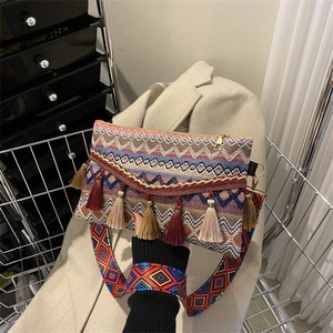 Detail of bohemian woven crossbody bag with colorful tassels and a patterned jacquard strap