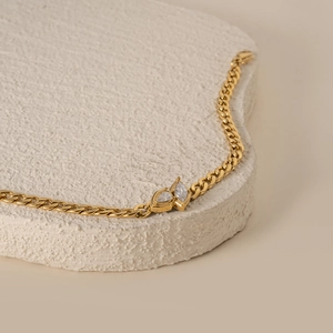 Detail of 18k gold plated Cuban link bracelet with pear-cut zircon stones on stone stand