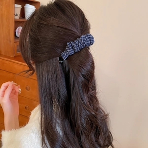 Vue détaillée d'une pince à cheveux en tissu à carreaux bleu marine sur cheveux longs