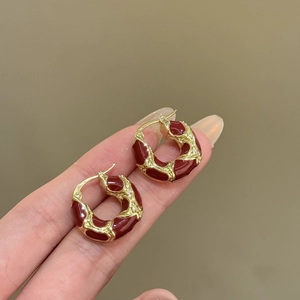 Detailed close-up of vintage red enamel hoop earrings with gold metal and small diamonds