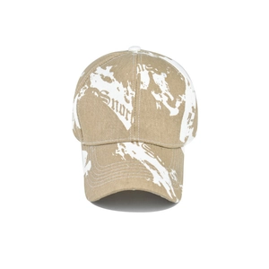 Detail of khaki tie-dye baseball cap featuring white graffiti and gothic lettering