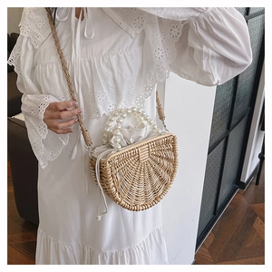 Detail of bamboo woven bag with large pearl handle and drawstring lining on white lace dress