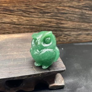 Close-up of a 3.5cm hand-carved green jade owl figurine with smooth natural stone texture
