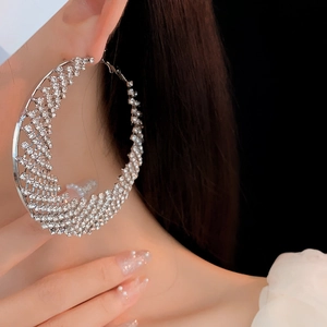 Macro close-up of a large silver hoop earring with sparkling rhinestones on a model