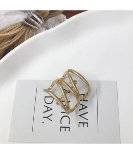 Close-up of a layered gold metal wrap ring on a minimalist white plate setting