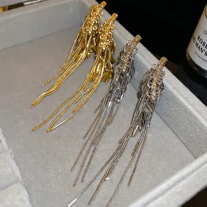 Long wheat spike tassel earrings in gold and silver finish on grey velvet background