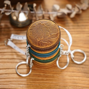 Macro shot of three vintage leather tape measures with floral embossing and keyrings