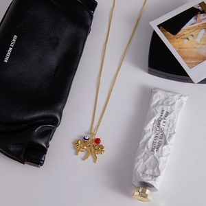Detailed flat lay of gold titanium steel necklace with lucky charm pendants on white surface