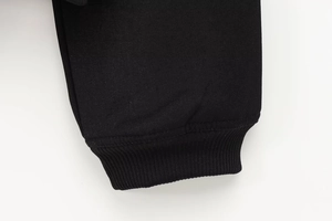 Detaillierte Nahaufnahme der schwarzen Rippbündchen und der Twill-Stoffstruktur der Jacke