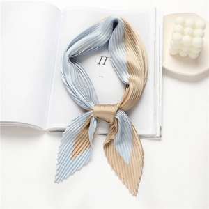 Pleated silk scarf in blue and champagne gold colors displayed on a white magazine
