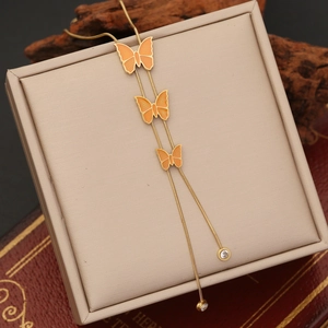 Detail of gold butterfly pendant necklace with orange enamel and clear zircon stones