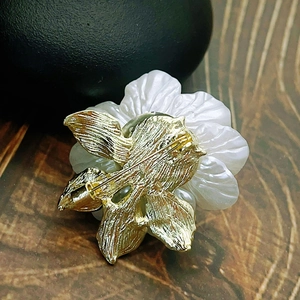 Close-up of pearl camellia brooch showing golden safety pin back and petal texture