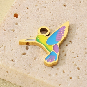 Detail of a gold stainless steel hummingbird charm with vibrant colorful enamel coating