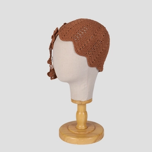 Detailed macro view of the handmade crochet weave and brown floral tassel on the beanie