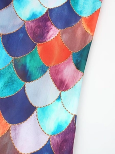 Close-up of vibrant mermaid scale fabric with golden chain texture on backless maxi dress