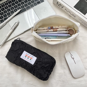 Top view of crinkled fabric pencil cases in black and cream showing large capacity