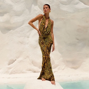 Sleeveless leopard print halter maxi dress with backless design on white rocks
