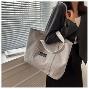 Detailed view of gray canvas tote bag texture with fashion label in sunlight shadows