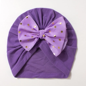 Purple baby turban hat featuring a large gold foil polka dot mesh bow on cotton fabric