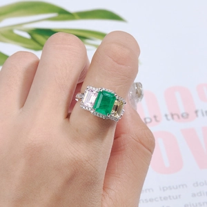 Macro shot of an emerald cut green stone with pink and yellow side gems on a silver band