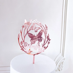 Macro detail of rose gold acrylic butterfly wreath cake topper with Happy Birthday text