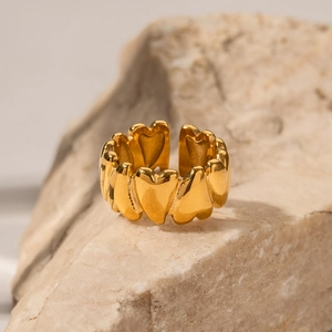 18K gold-plated stainless steel heart ring displayed on a natural beige stone pedestal