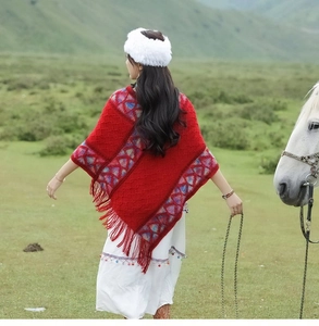 Detail of red ethnic style hooded poncho with colorful geometric patterns and tassels