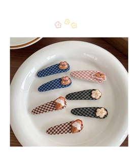 Detailed close-up of colorful checkered fabric hair clips with cute cartoon animal decorations