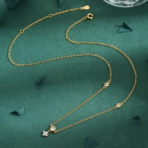 Elegant gold necklace with clover petal pendant and round zircon accents on dark background