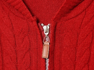 Détail d'un pull en maille torsadée rouge avec zip en métal et tirette en cuir