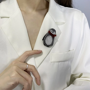 Fashionable grey penguin acrylic brooch with red scarf on a white suit jacket lapel