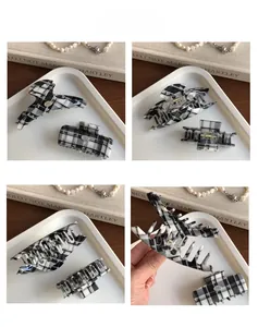 Detail of black and white checkered hair claw clips with silver logo and metal springs